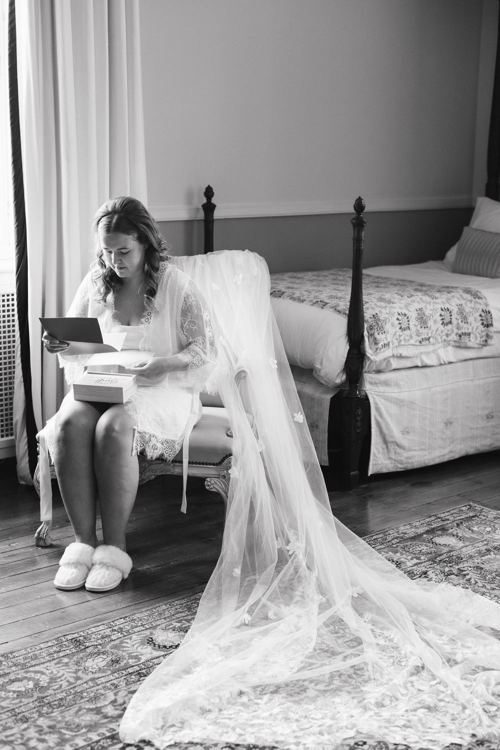 A bride in a flowing white veil and gown sits on the floor in a series of artistic black and white photos.