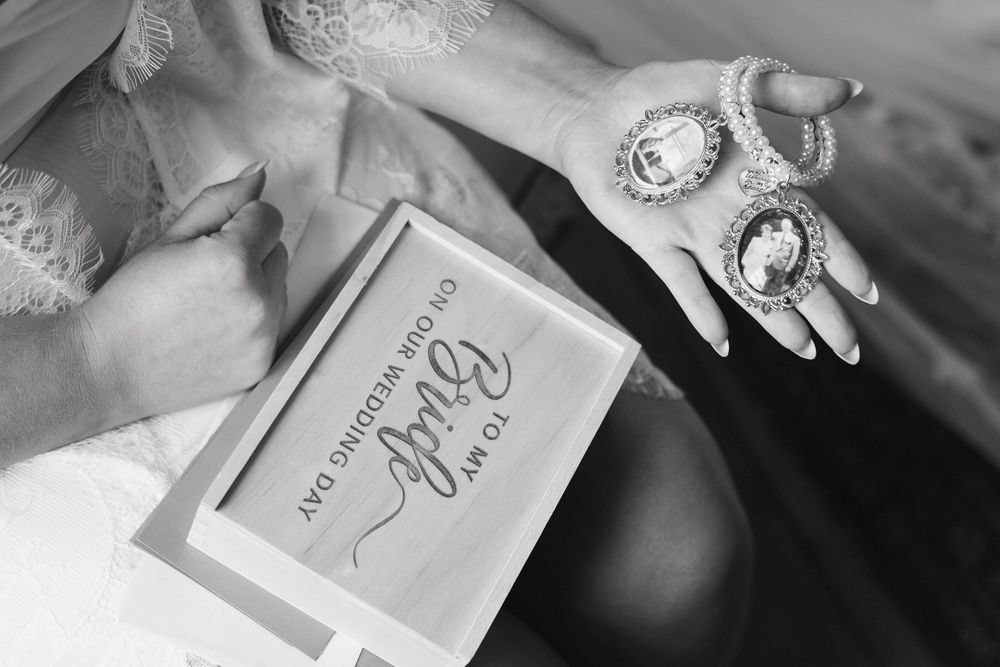 Wedding accessories including pearl necklaces and decorative items arranged on a wooden surface in monochrome.