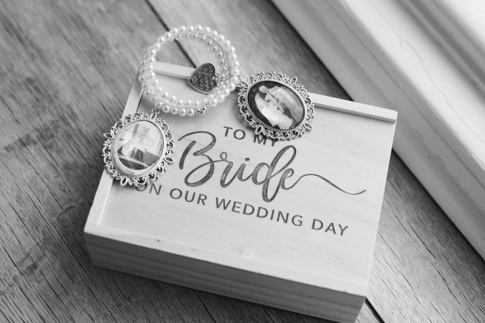 Wedding stationery and pearl accessories displayed on a rustic wooden surface in black and white.