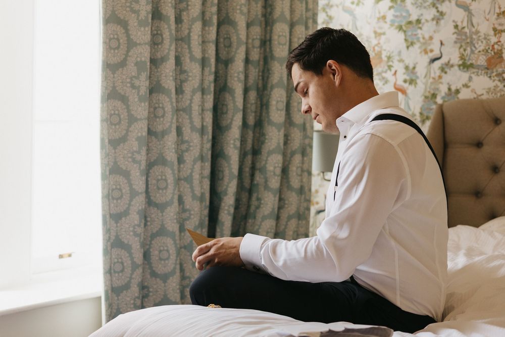 Black and white photo of someone in a white dress shirt writing at an elegant upholstered settee.
