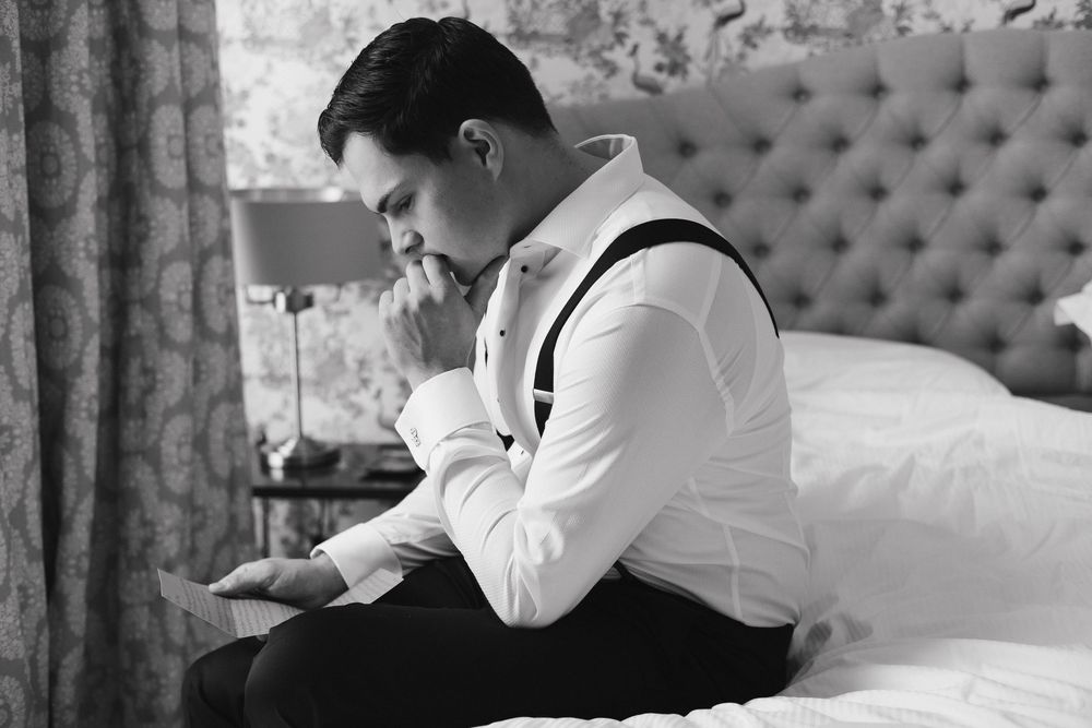 Person in formal attire writing in a journal while seated on a tufted couch.