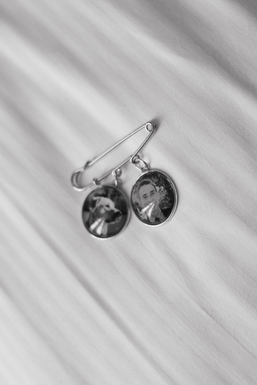Silver cufflinks resting on a white textured surface in black and white photography.