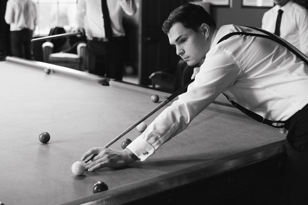 Side view of a player leaning over the snooker table aiming for a precise shot.