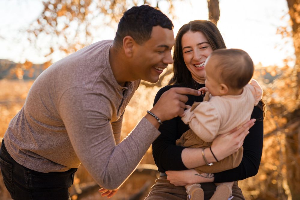 Family sharing tender moments together during golden hour sunset in a natural outdoor setting.