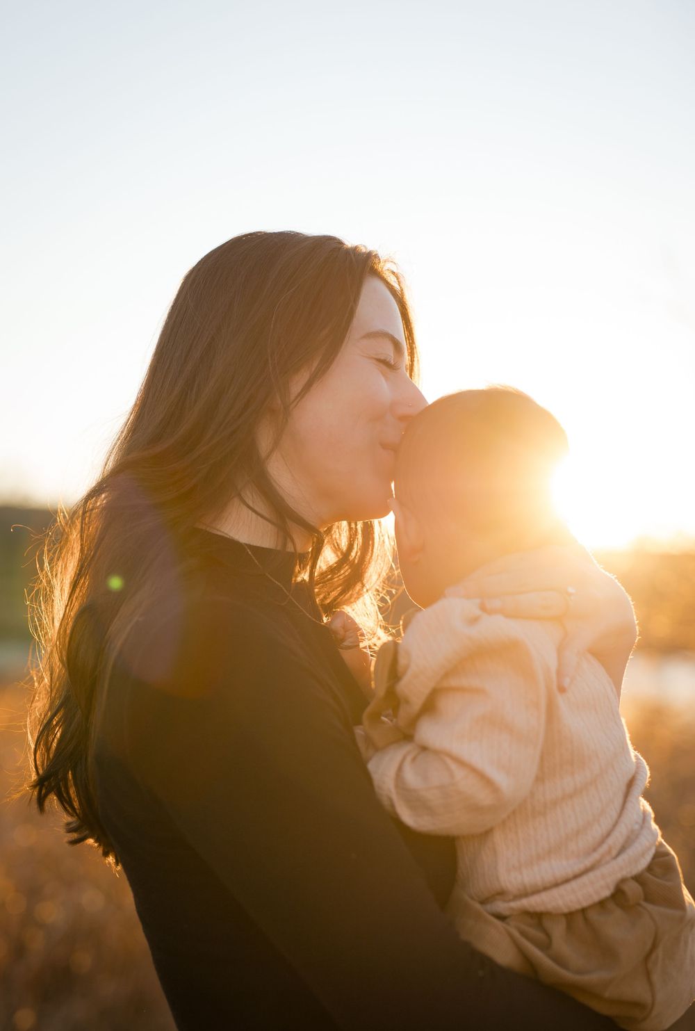 Mother and baby sharing intimate bonding moments against a bright sunlit background.