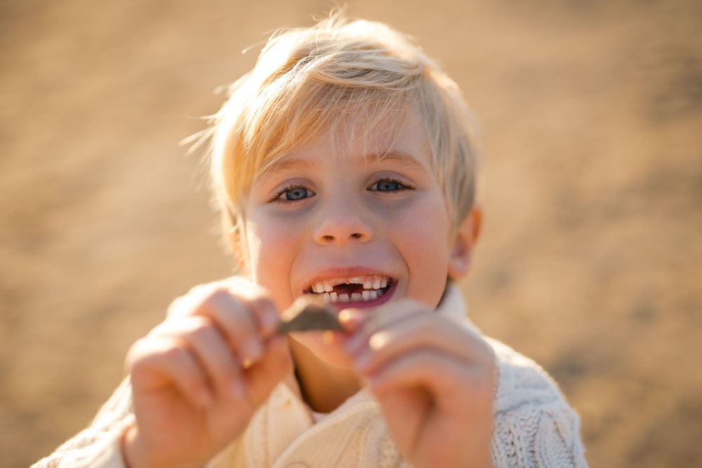 A series of candid outdoor photos showing a child laughing and making silly faces in warm sunlight.