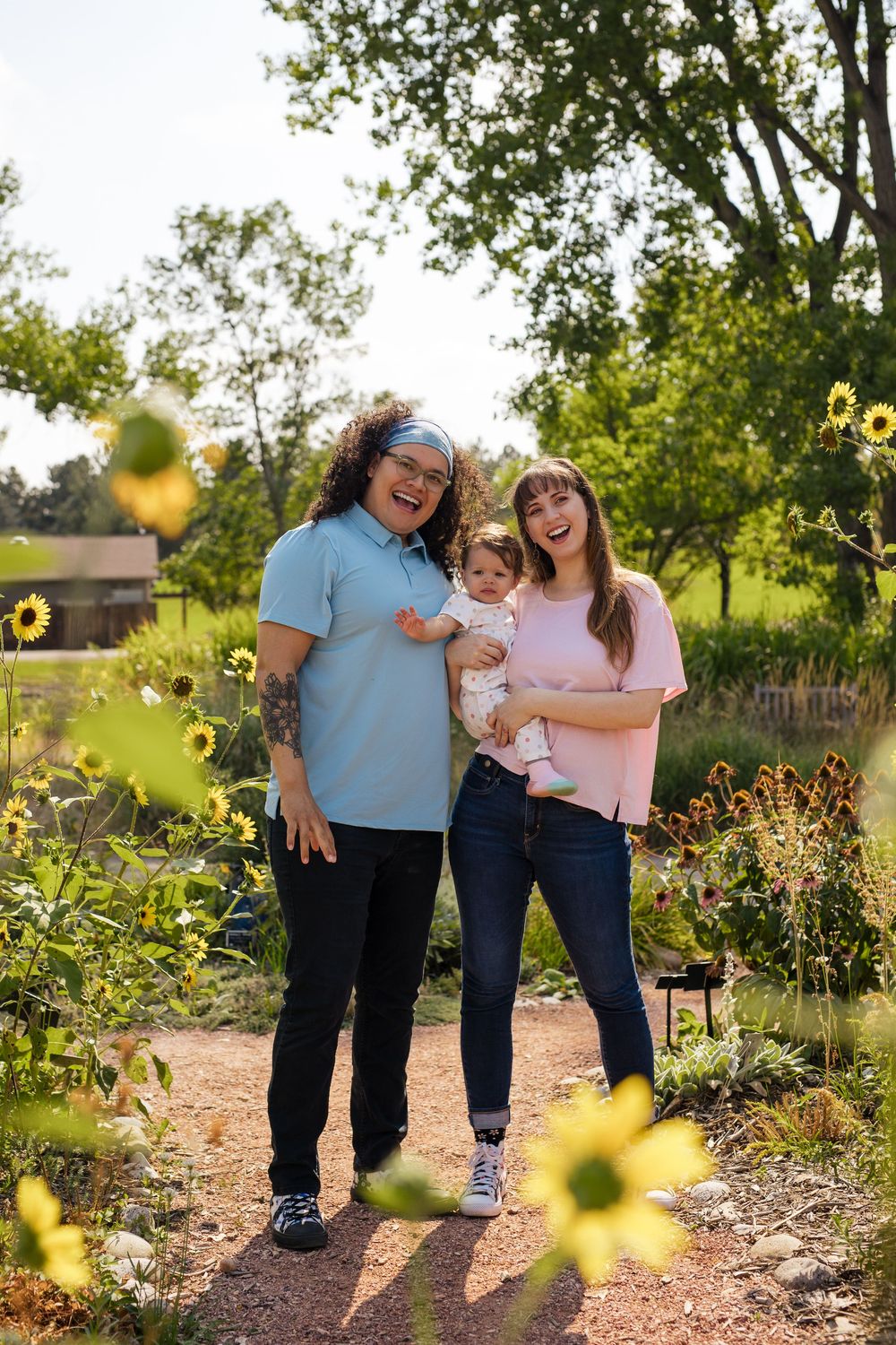 Family sharing joyful moments together in a sunlit garden with blooming sunflowers in the background.