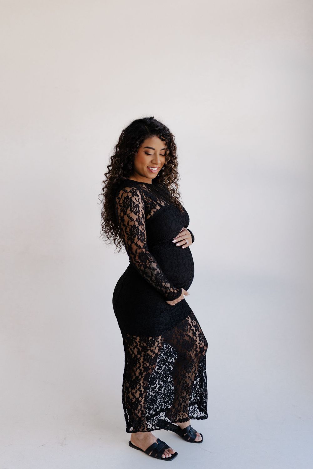 A figure in a black lace dress and slides poses against a white background in a series of artistic portraits.