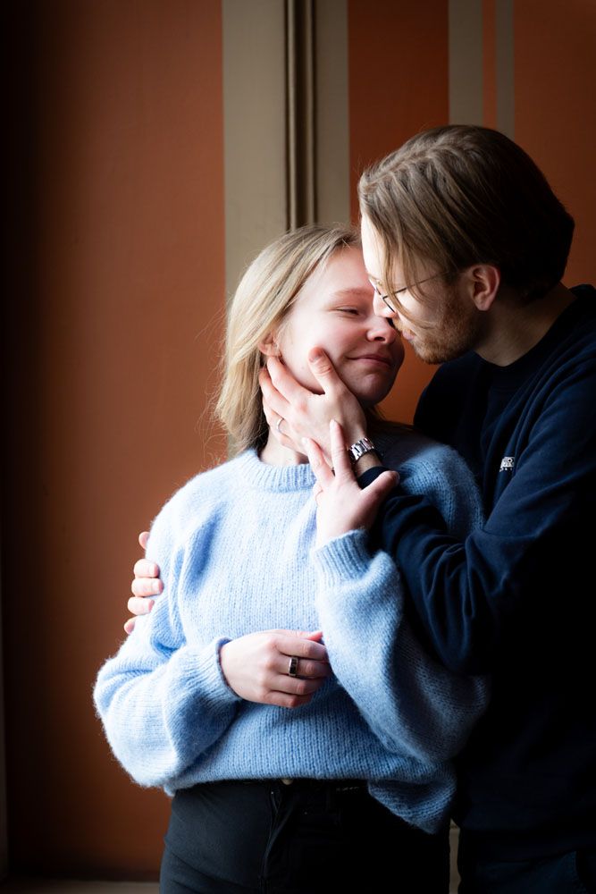 Pariskunta on lähekkäin hellästi kauniissa oranssissa käytävässä luonnonvalossa.