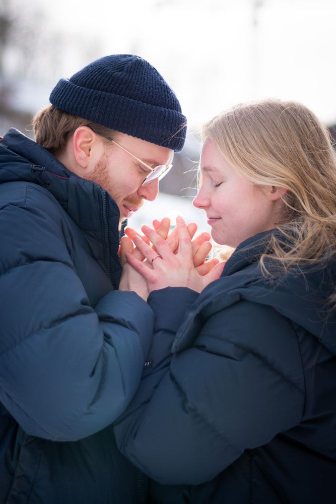 Toppavaatteissa oleva pariskunta pitää käsiään yhdessä päidensä välissä ja puhaltaa käsiin lämmitellen niitä.