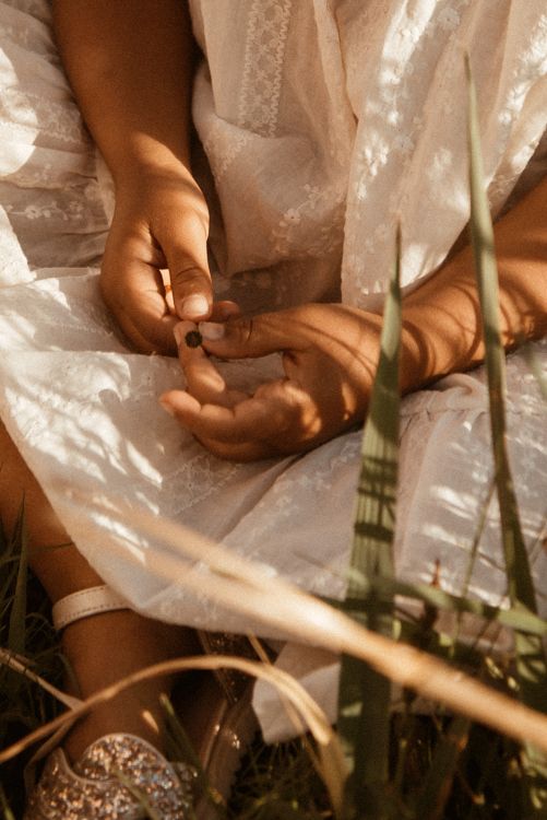Close-up of hands delicately holding something in a white lace dress setting with soft lighting, during a family photoshot in Didsbury.
