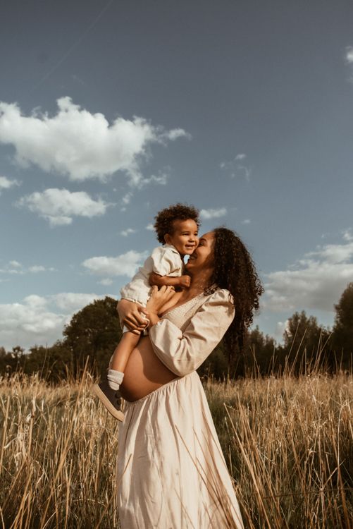 Didsbury family photographer captures a photo of Mother and child share tender moments together in a golden wheat field under a cloudy sky.