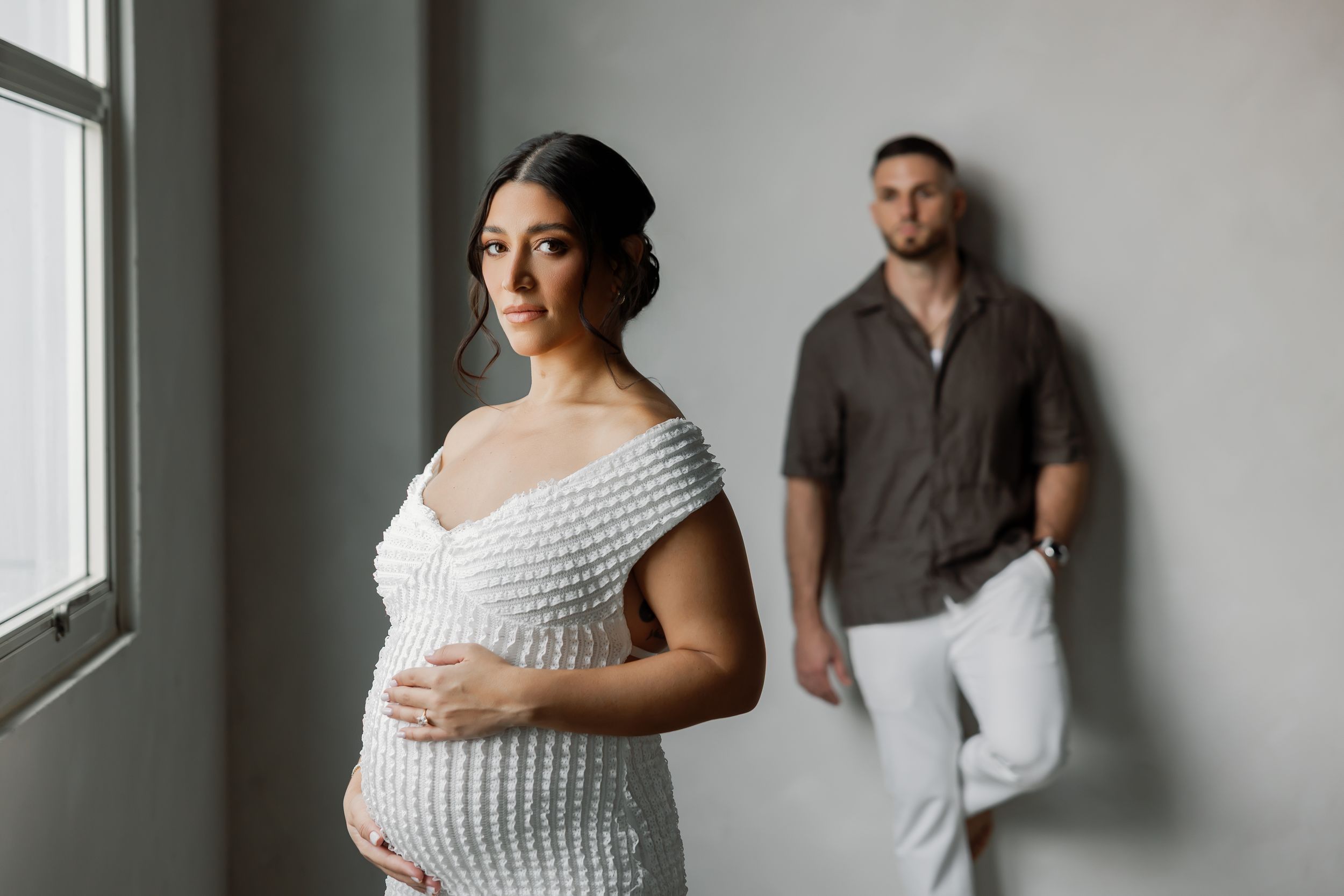 A pregnant woman and her partner standing together in a studio.