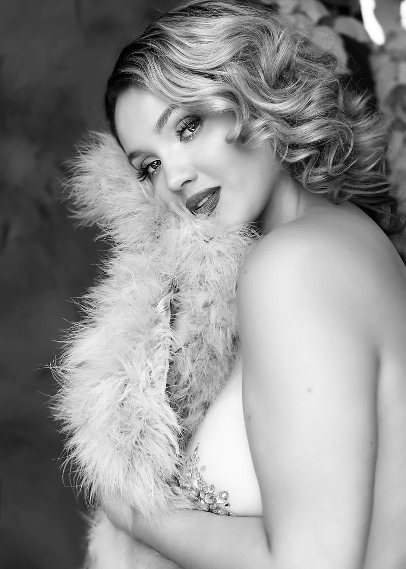 Glamour portrait with dramatic makeup and feather boa in black and white.