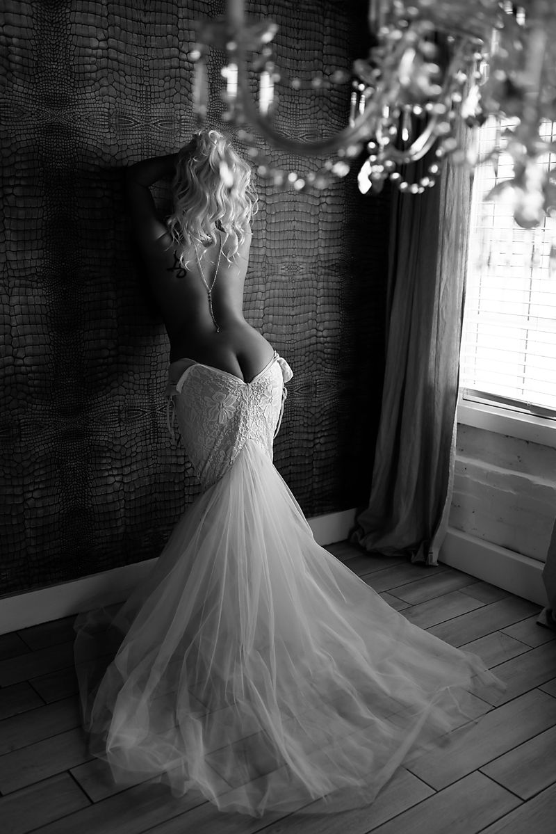 Dramatic black and white photo of flowing strapless wedding dress with ethereal tulle skirt in window light.