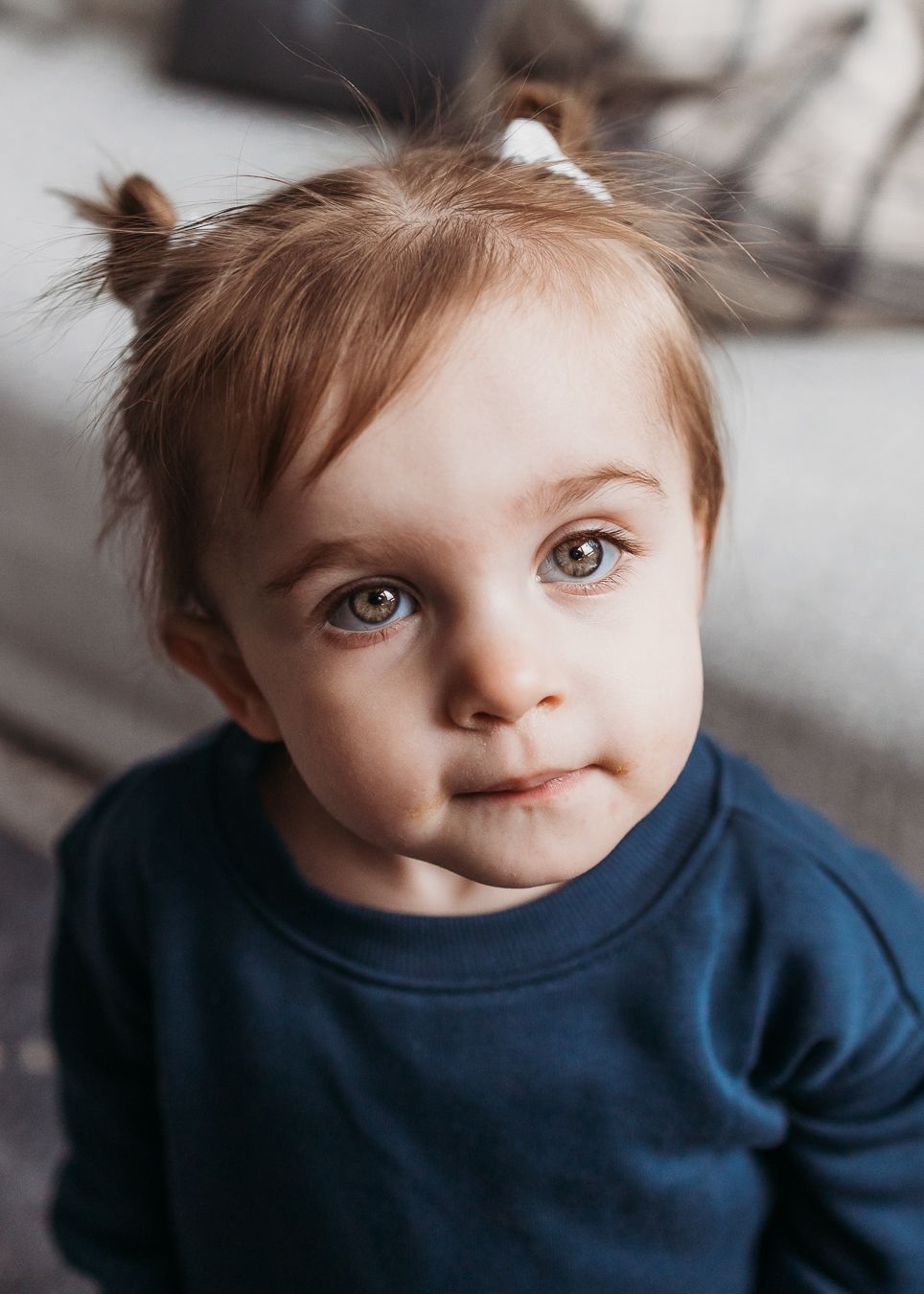 A young child in a navy blue sweater looks up with bright blue eyes in a series of candid portrait shots.