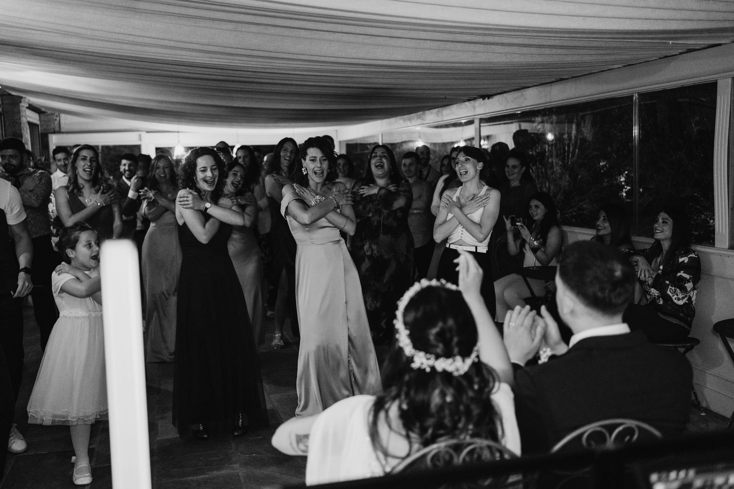 Black and white photo of wedding guests reacting emotionally during a heartfelt reception moment.
