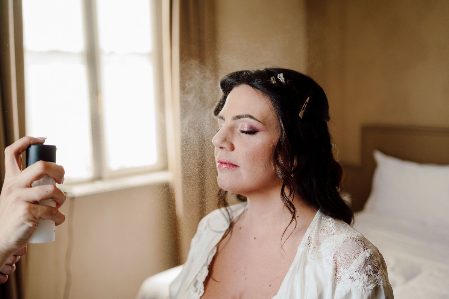 Makeup artist setting the brides look with a finishing spray before the wedding.