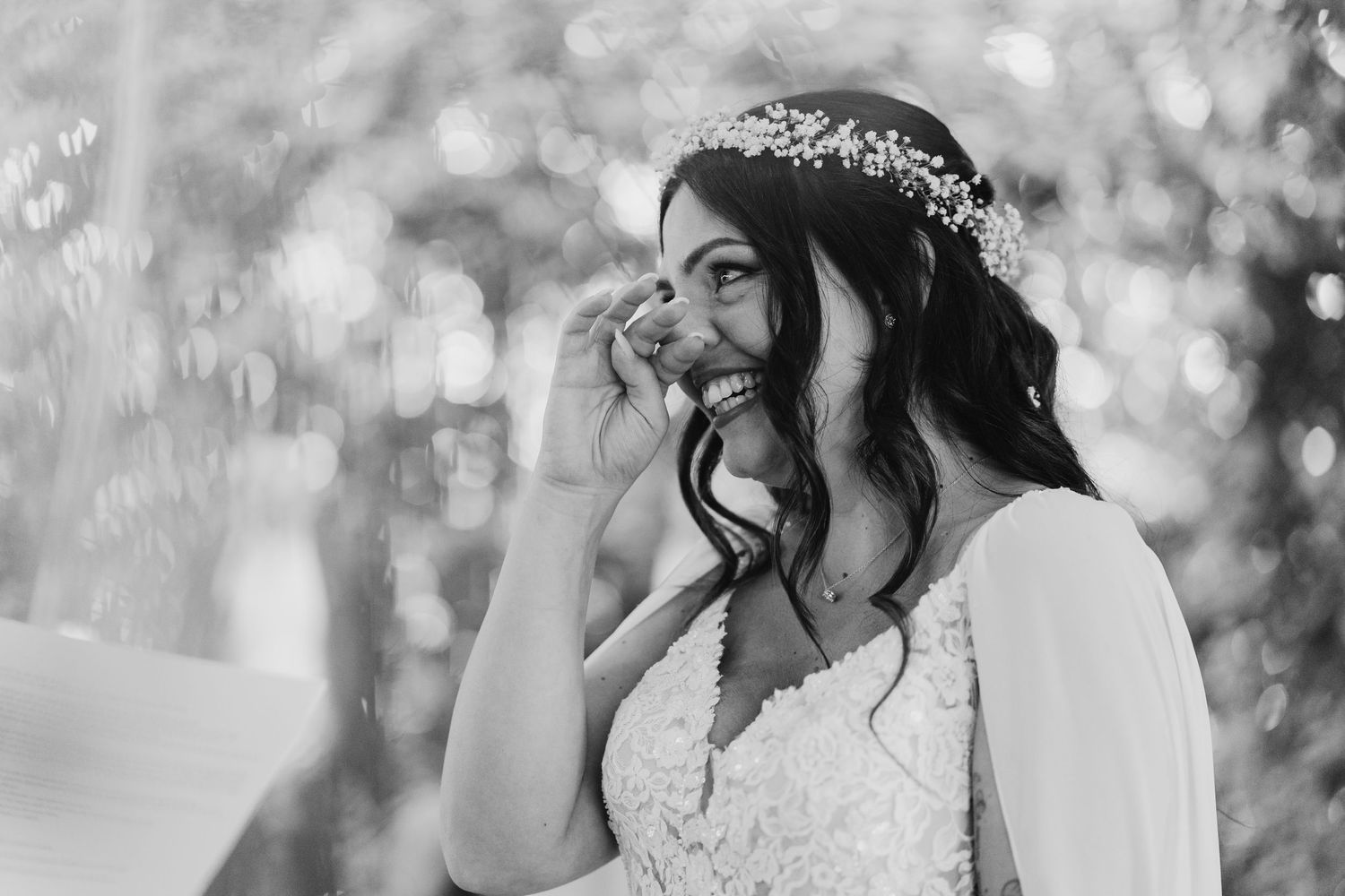 Black and white portrait of a laughing bride wearing a floral crown on her wedding day.