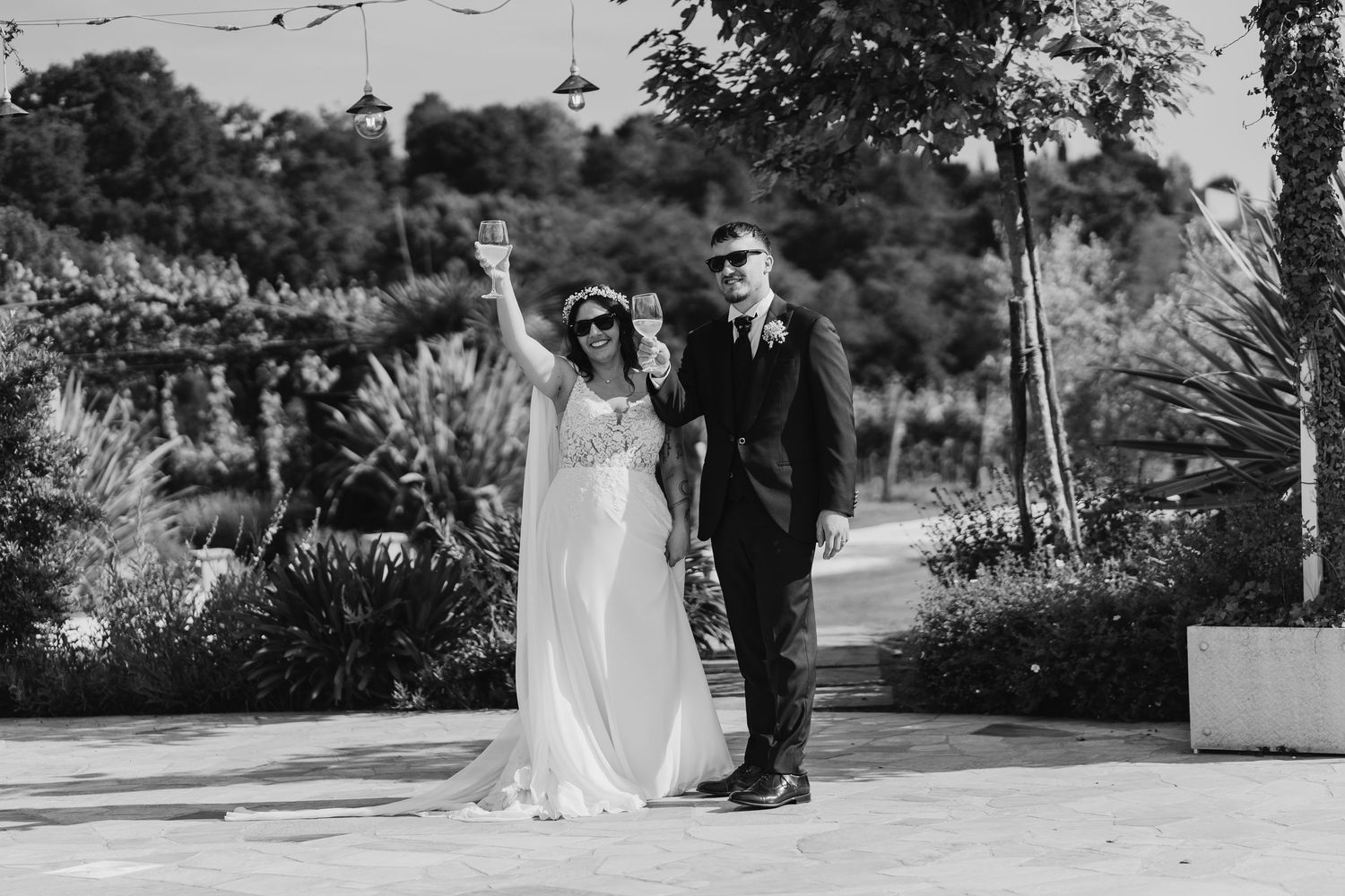 Black and white photo of a joyful bride and groom walking together at their outdoor wedding celebration.