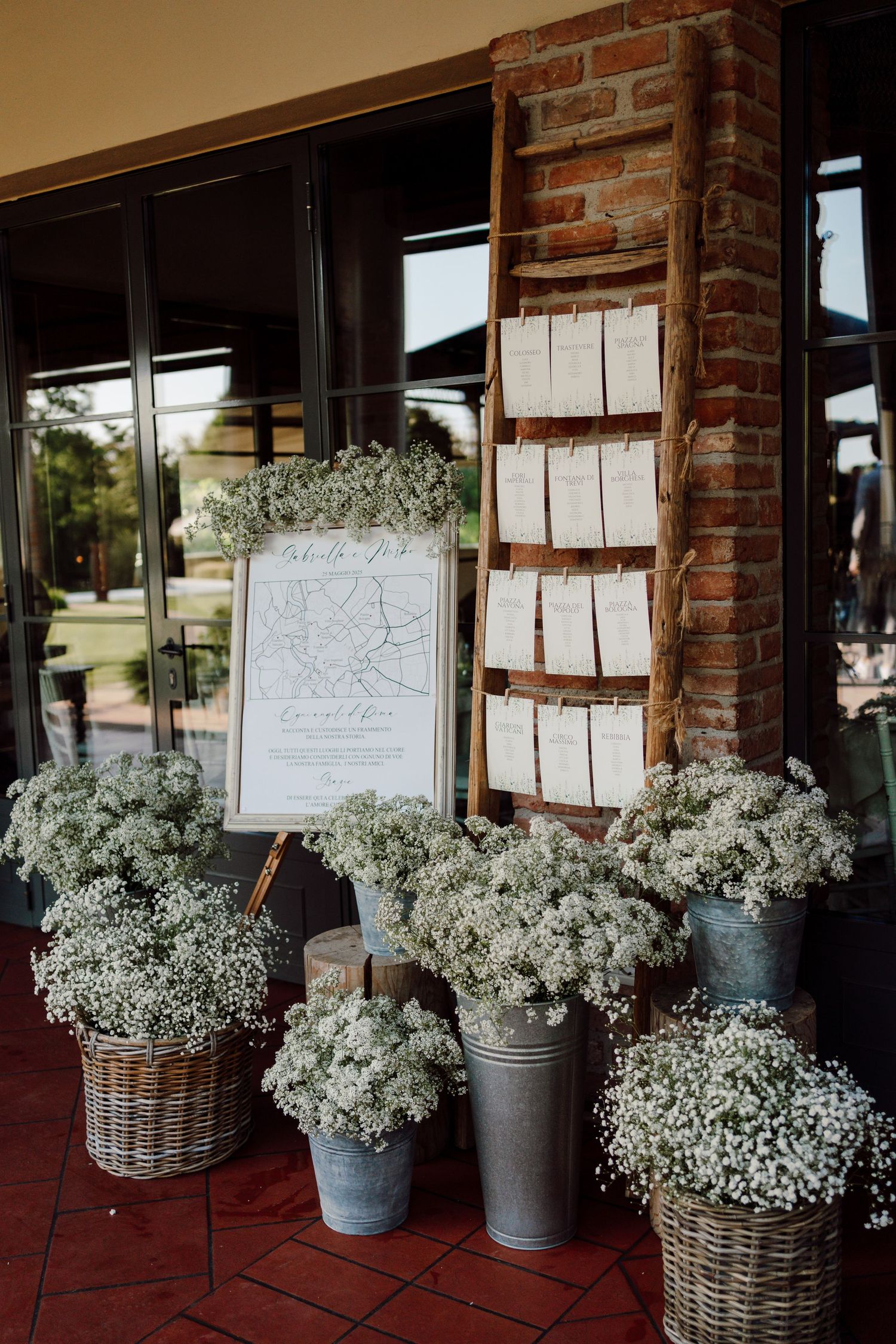 Rustic wedding seating chart display with baby's breath floral arrangements in wicker and metal buckets.