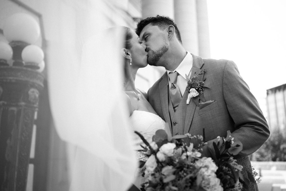 Close-up romantic moment between newlyweds with bridal bouquet.