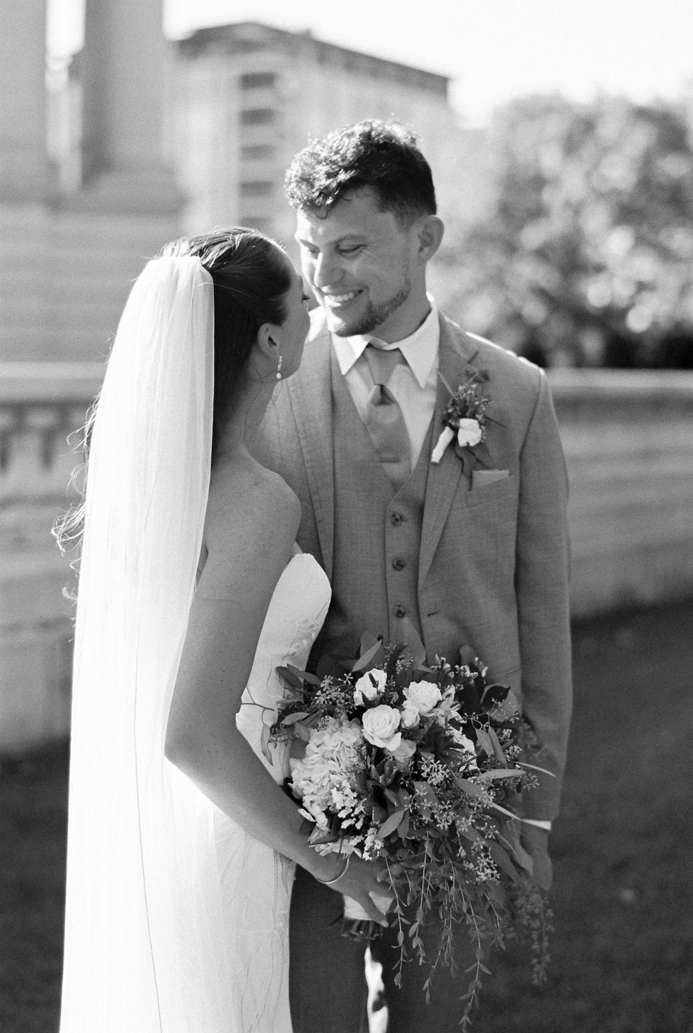 Black and white wedding photos showing tender moments between newlyweds with bouquet.