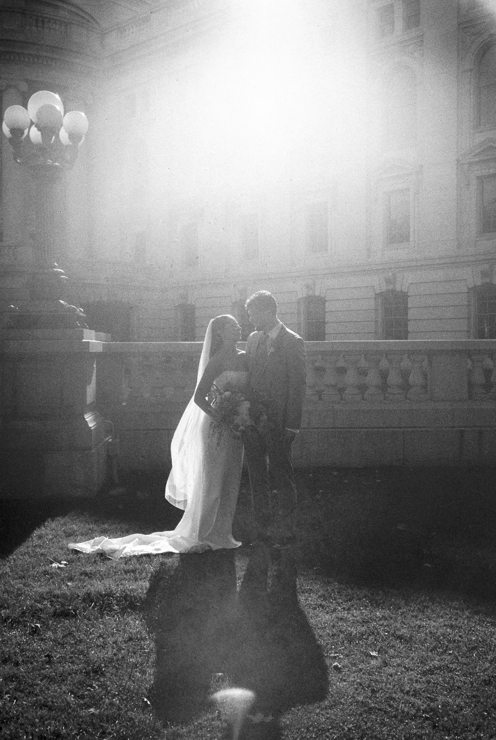 Black and white wedding photos capture tender moments between newlyweds against an elegant architectural backdrop.