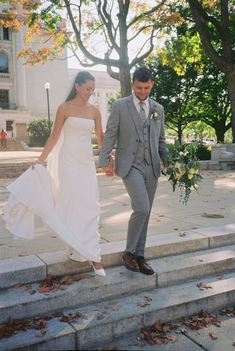 A sequence of wedding photos shows a couple playfully descending stone steps surrounded by autumn leaves and trees.