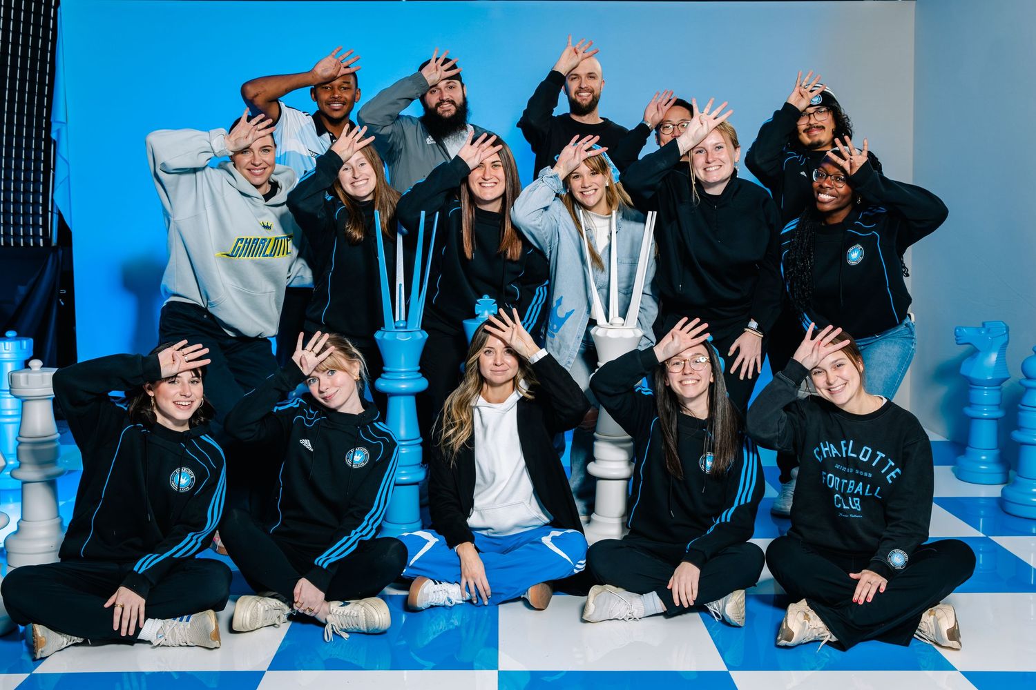 Charlotte FC fans and influencers pose on chess board set for Carolina Kit Crowns Up launch.