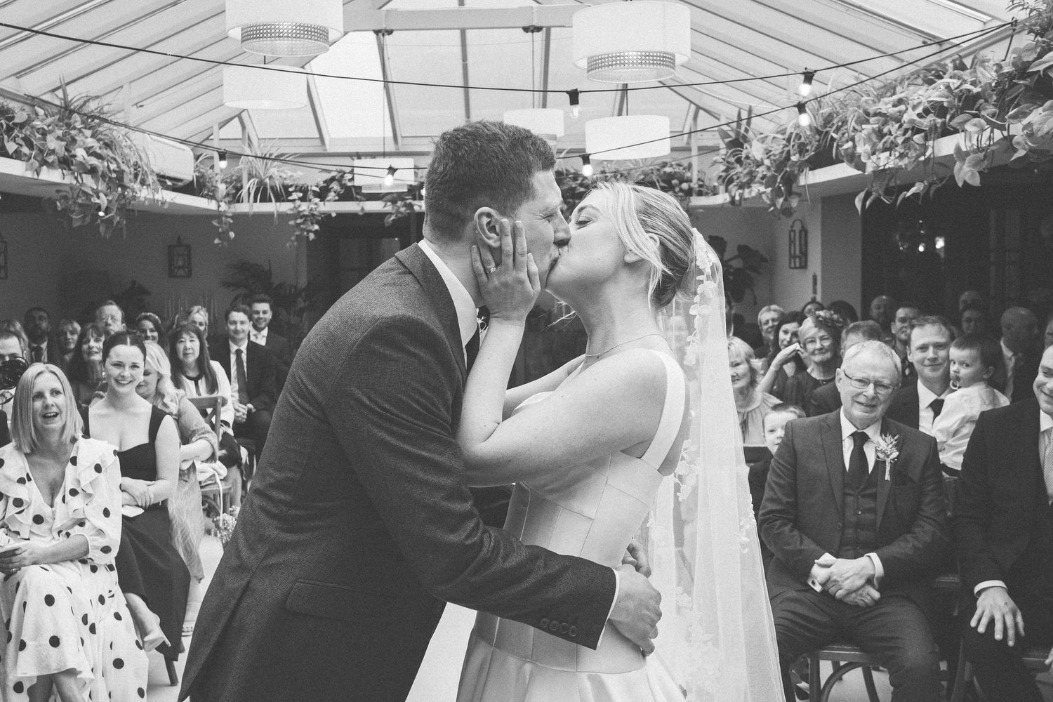 Black and white wedding portrait outdoors against stone wall backdrop.