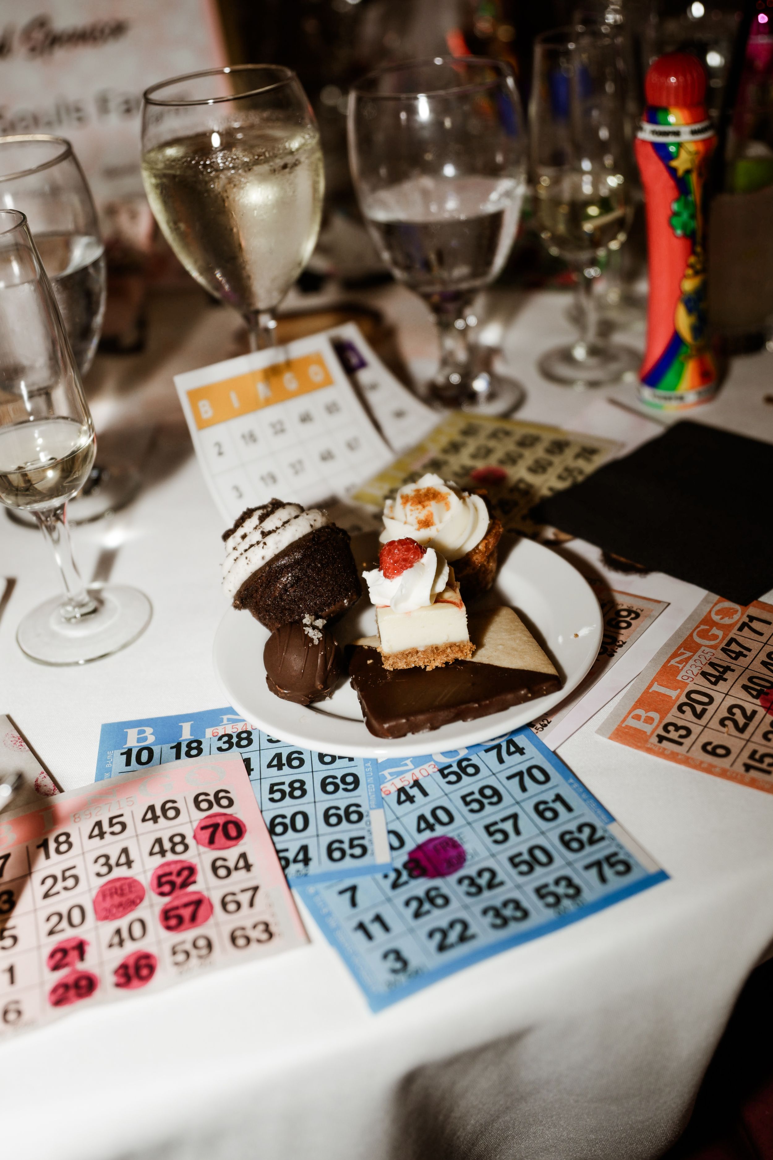 Colorful bingo cards surround a dessert plate with champagne glasses at a luxury bingo charity fundraiser event.