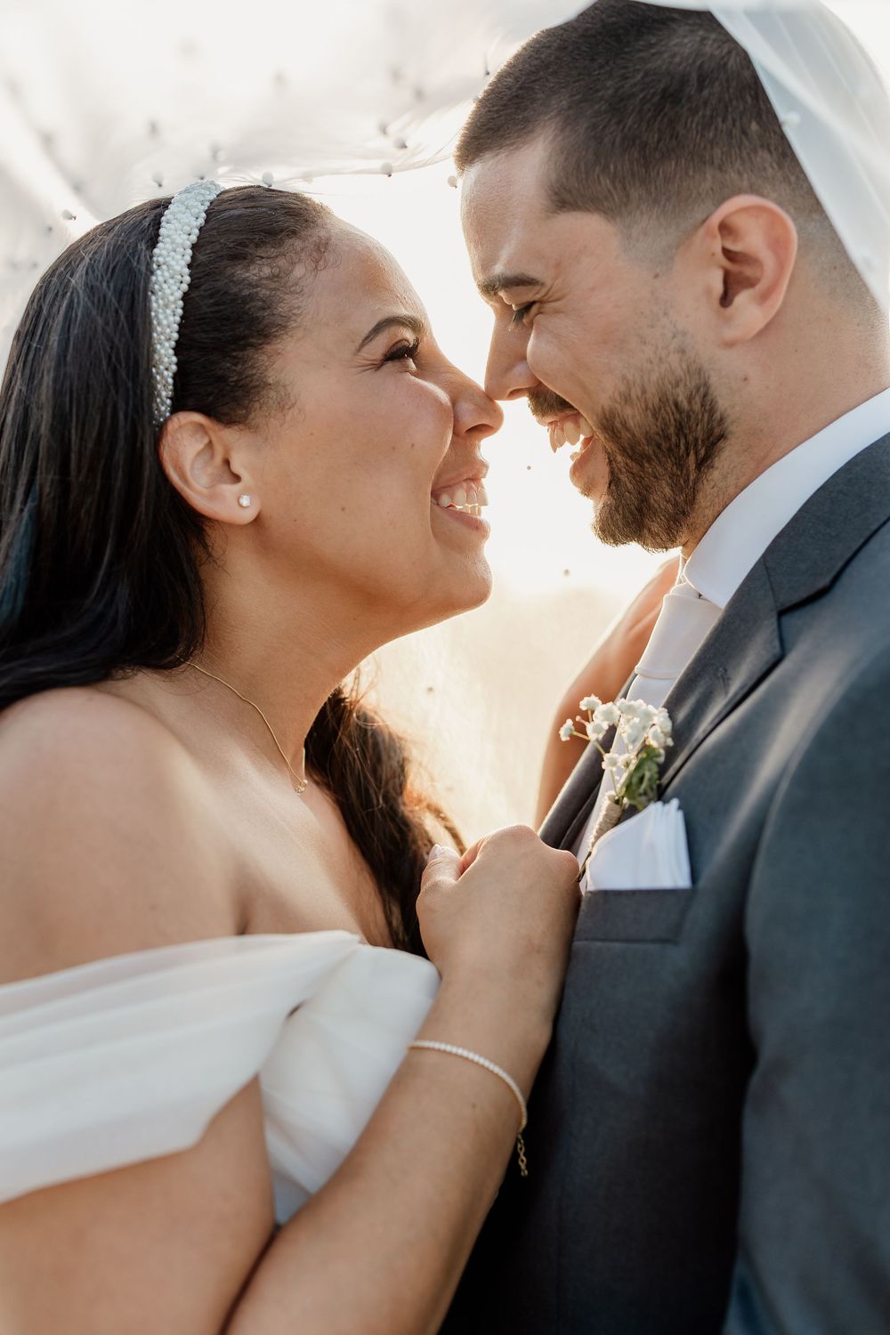 A romantic wedding couple embraces in sunlit portraits showing tender moments between them.