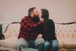 Couple sharing romantic moments together on a white couch in a living room setting.