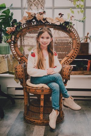A series of photos showing someone sitting in a vintage rattan peacock chair surrounded by green plants.