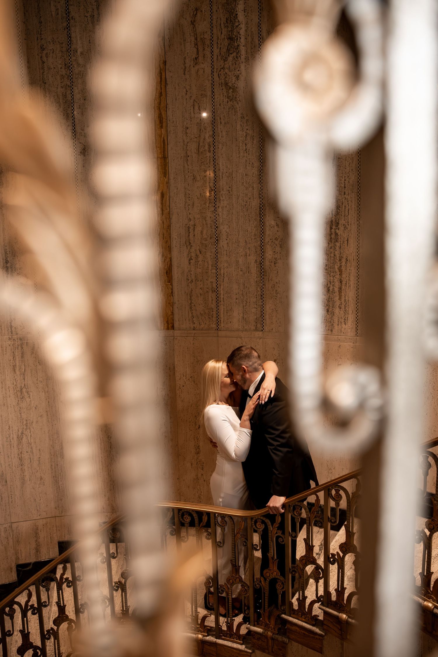 Couple hugging and looking at each other intimately through the trellis of a staircase at Bottleworks Hotel, Indy engagement session