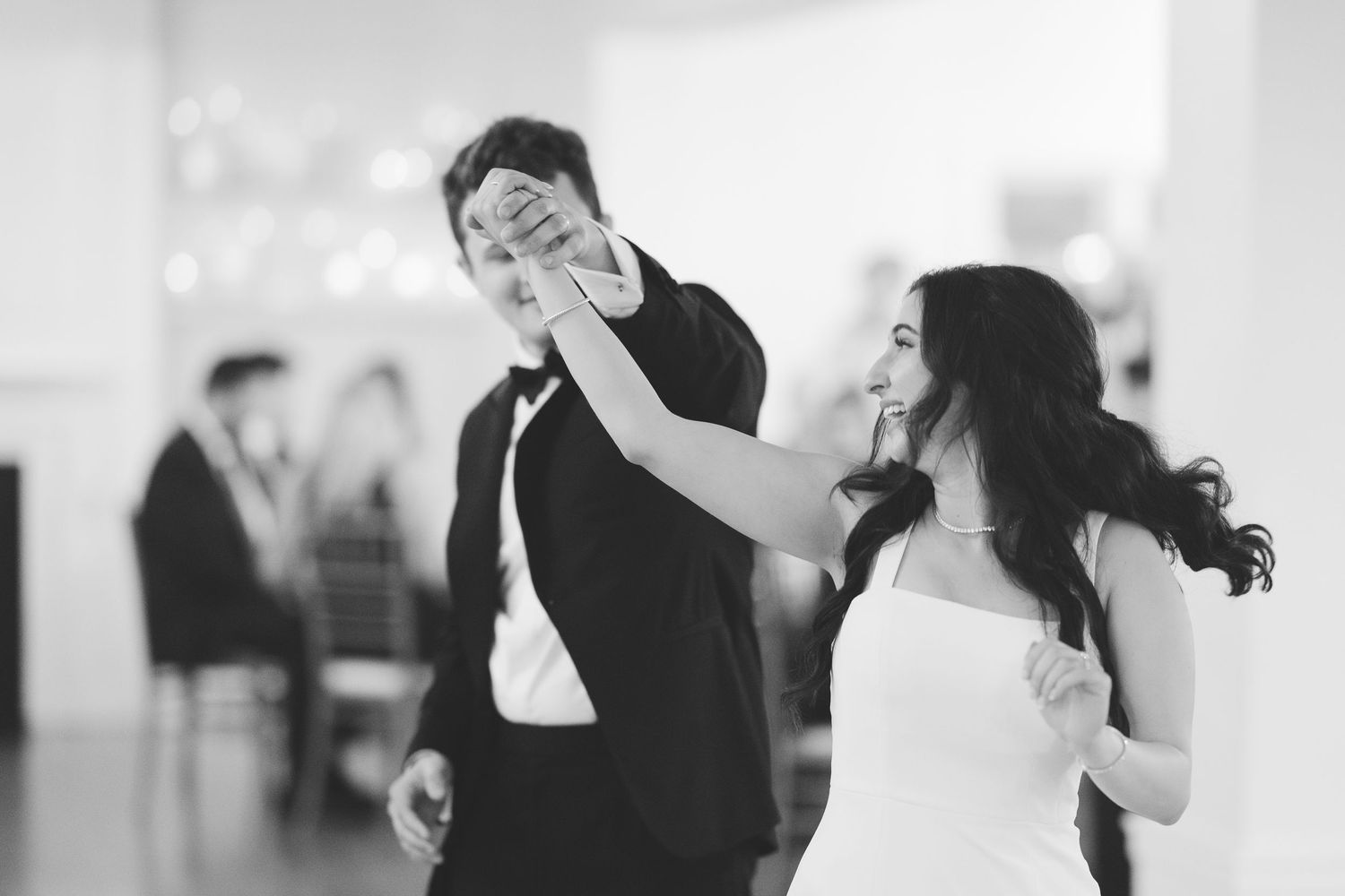 Black and white photo of bride and groom sharing playful first dance at wedding reception.