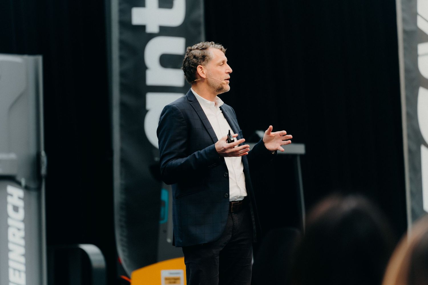 Professional speaker presents passionately on stage at a business conference with animated hand gestures.