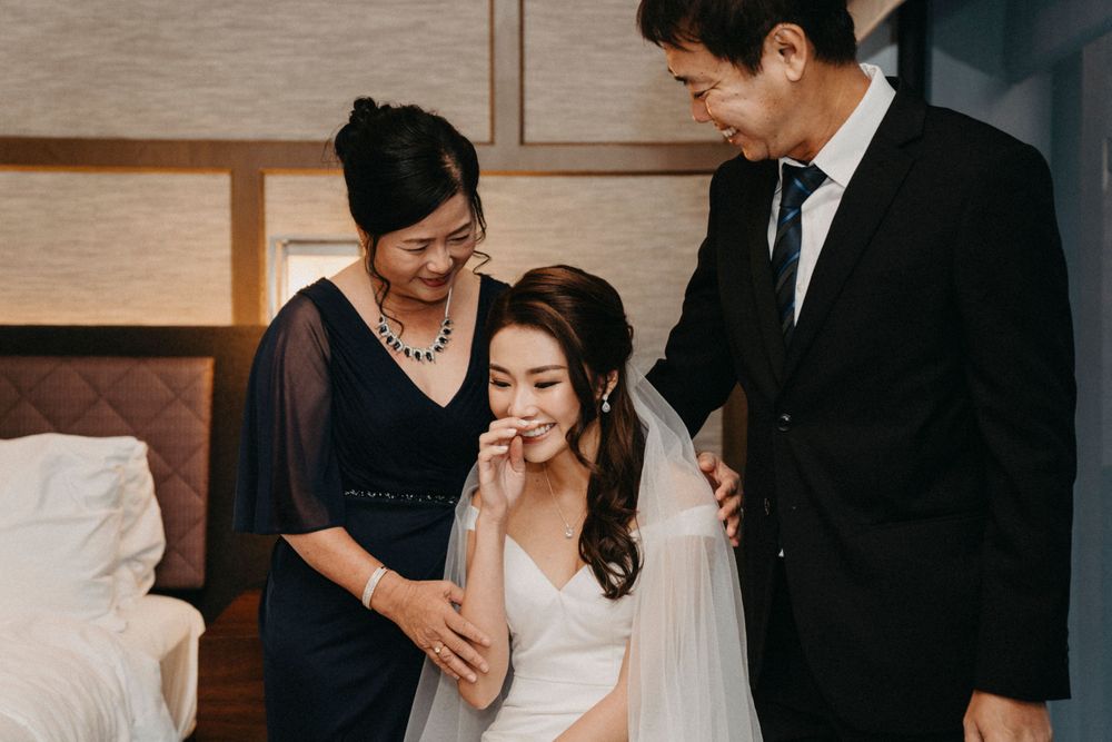 An intimate pre-wedding preparation moment in a hotel room with formal attire.