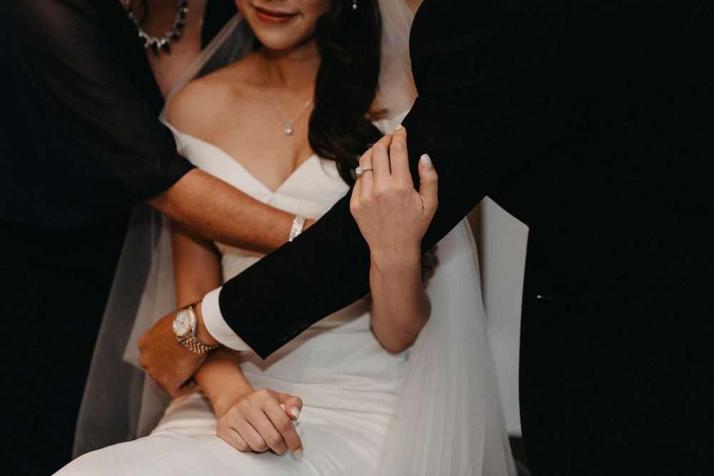 Close-up of a couple's hands with the bride wearing a white dress during an intimate wedding moment.