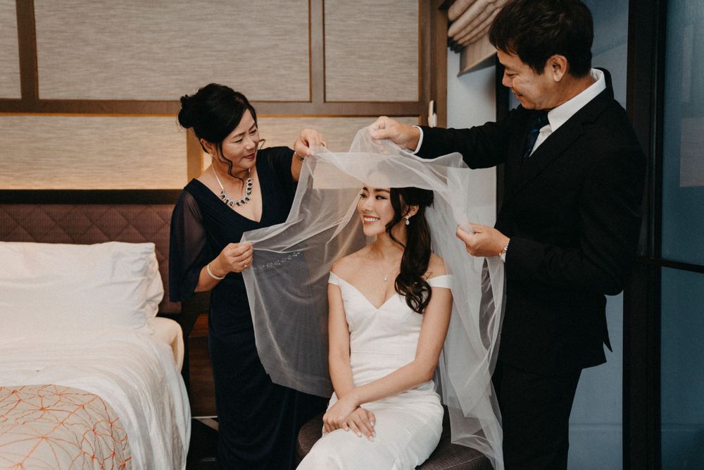 Wedding preparation scene showing final touches being made to the bride's veil in a hotel room.