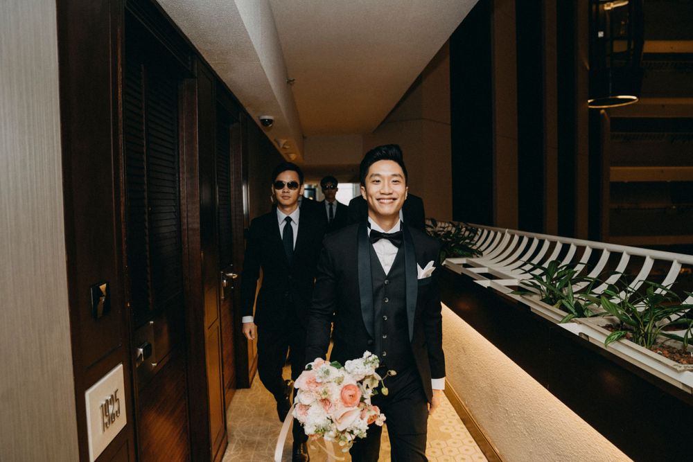 Wedding party walking through an elegant hotel corridor carrying bouquets.