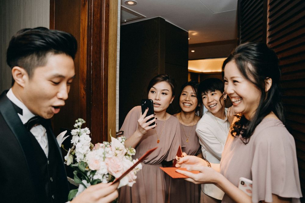 Wedding party gathering in a hotel hallway with bouquets and formal attire.