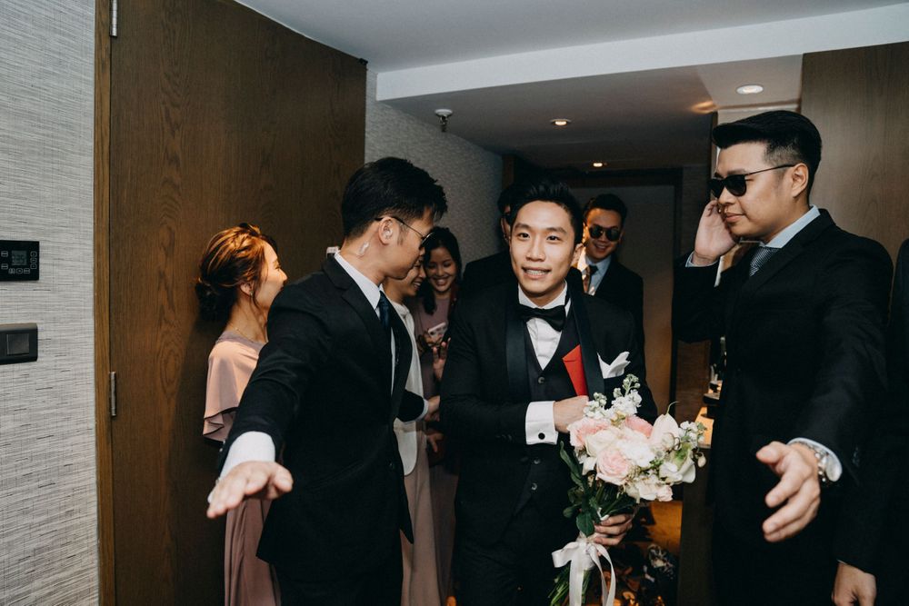 Groomsmen and wedding party members gathered in a hotel hallway during celebrations.