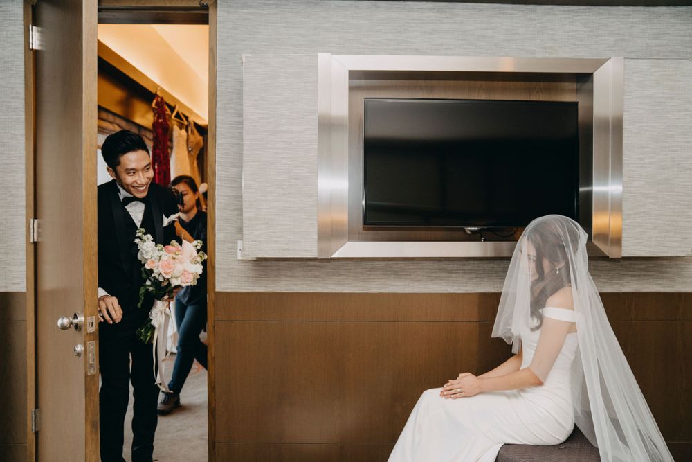 Romantic first look moment between couple in formal wedding attire in hotel room.