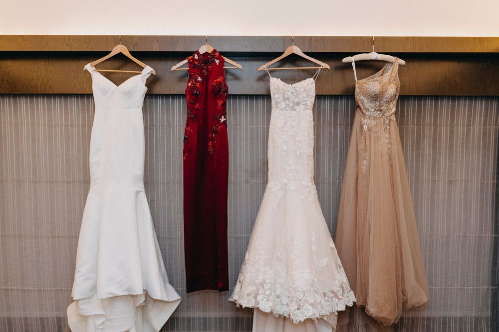 Wedding dresses in white, red and champagne colors hang on display.