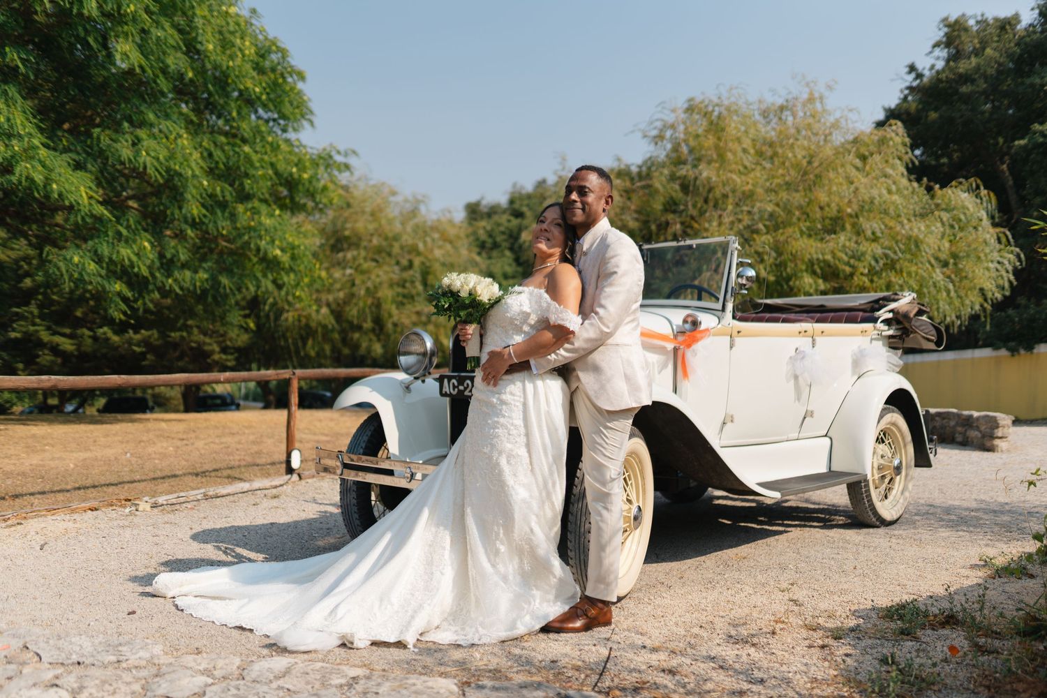 Vintage white convertible car parked in a sunny outdoor setting for a wedding photoshoot.