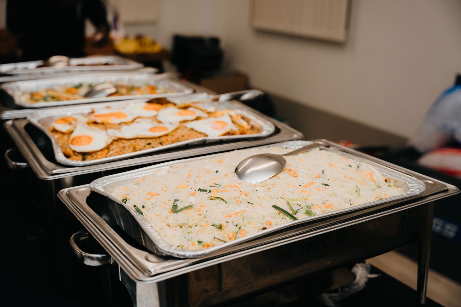 A close-up view shows pizza dough being stretched and shaped on a professional stainless steel prep surface.