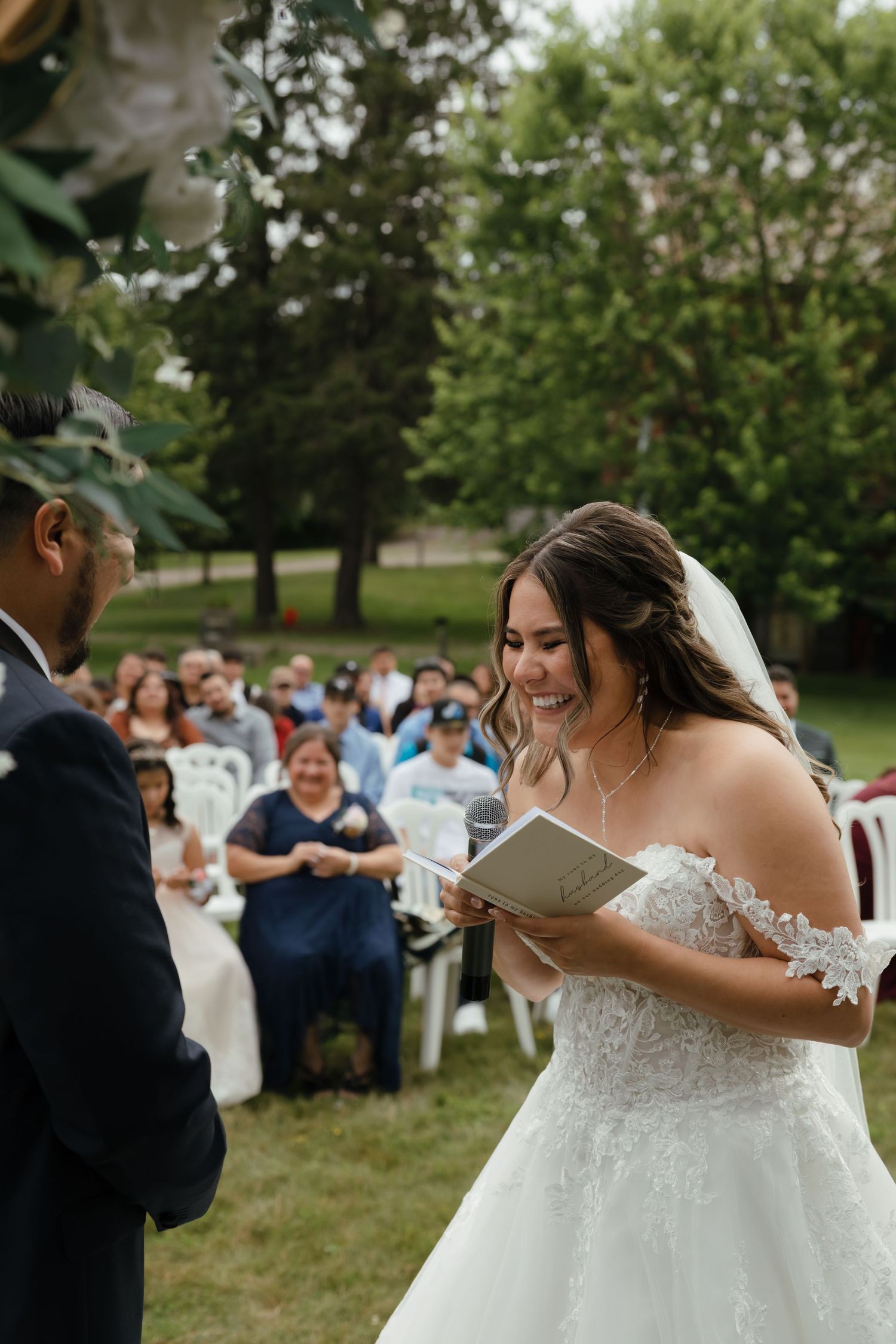 Wedding guests gather outdoors in a grassy garden setting watching an emotional moment during the ceremony.
