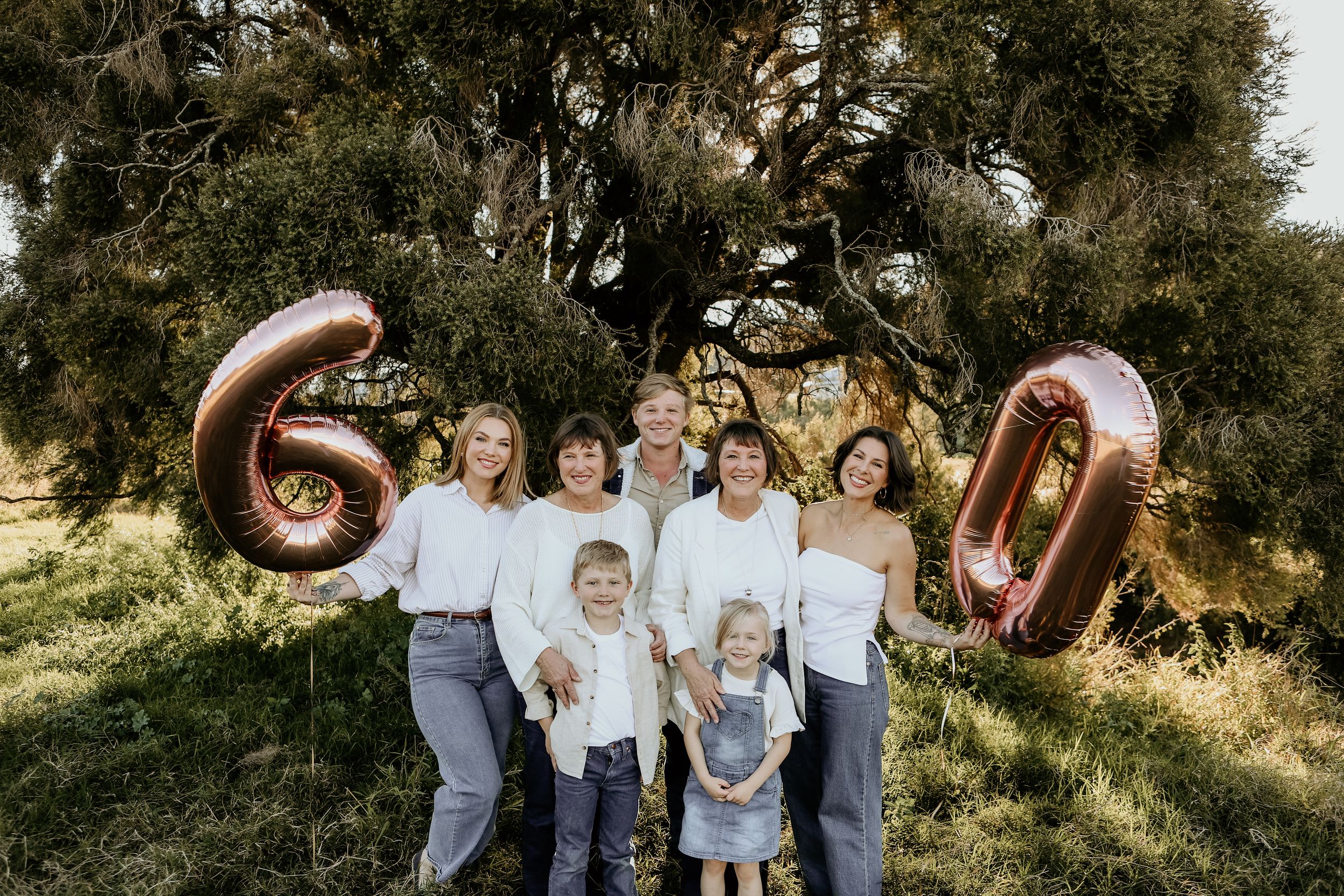 Family group photo session in a scenic outdoor setting with trees at sunset.